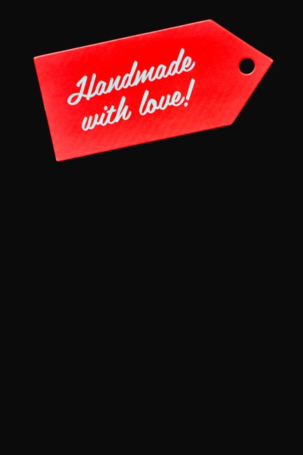 A close-up view of a bright red, rectangular gift tag with rounded corners and a small black hole in the top right corner, featuring white cursive text that reads 'Handmade with love!' The tag appears to be made of sturdy paper or cardboard and is set against a plain black background. This image likely depicts packaging or decorative tags that may be used during packing or gifting processes associated with house removals. The focus on the tag's design and message complements themes of careful packing and attention to detail typical of professional removal services such as Man with Van Belvedere, especially when preparing belongings for a home relocation or furniture transport.