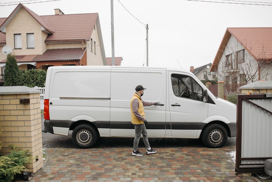 A white panel van is parked on a paved driveway with cobblestone tiles, facing forward with the driver's side visible. The van is part of a house removal or moving service by Man with Van Belvedere, p